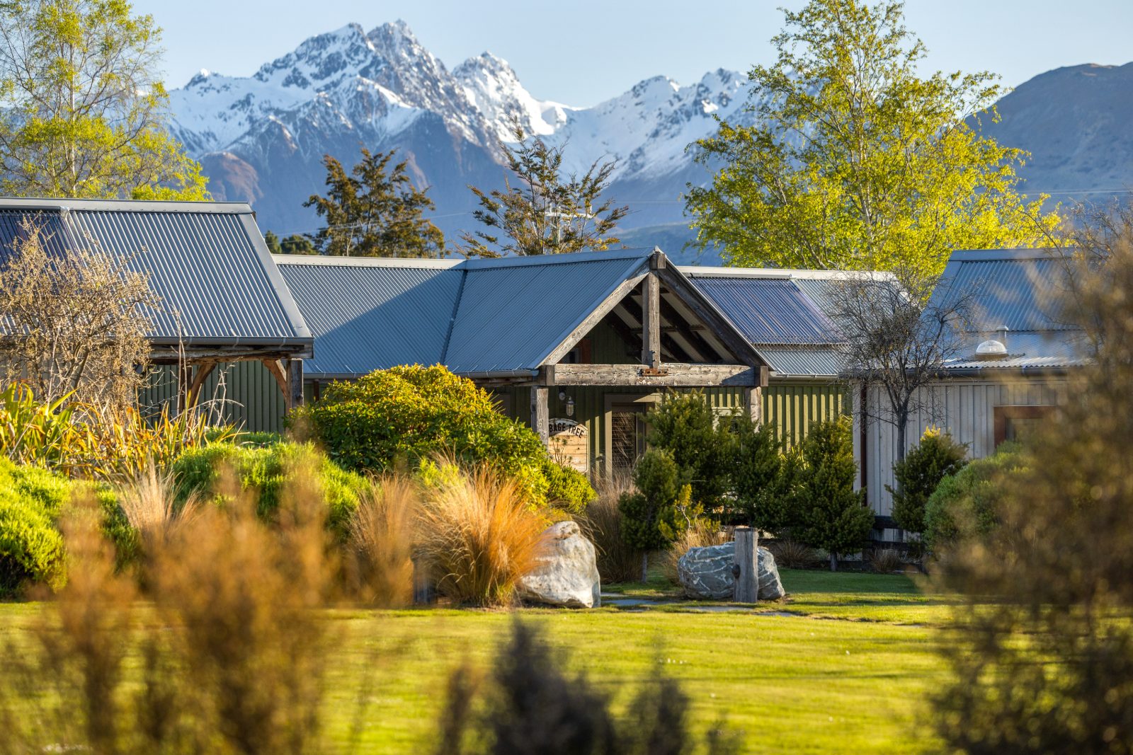 A chalet at The Headwaters Eco Lodge in spring, with the Southern Alps behind